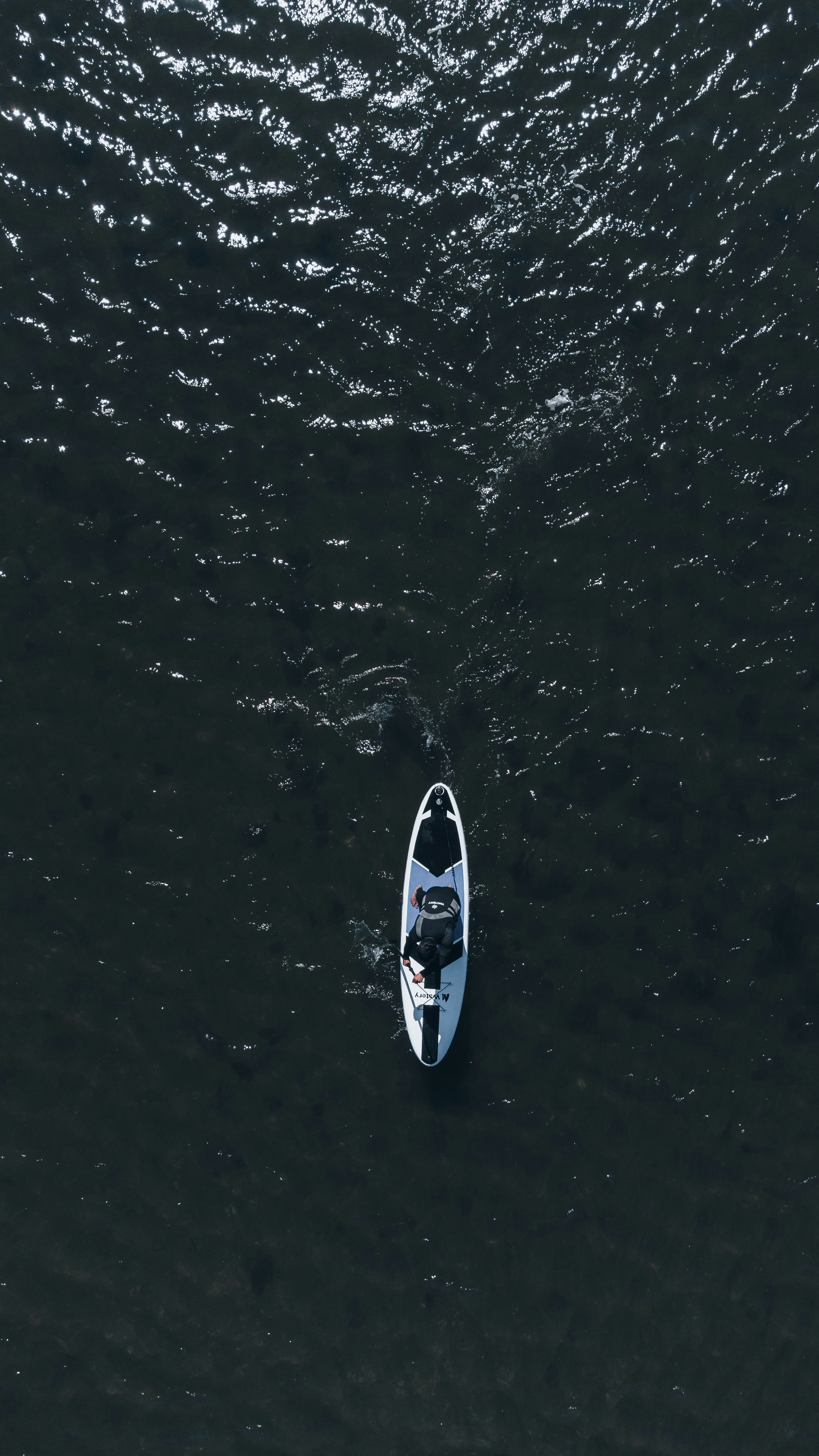 white and black surfboard on body of water